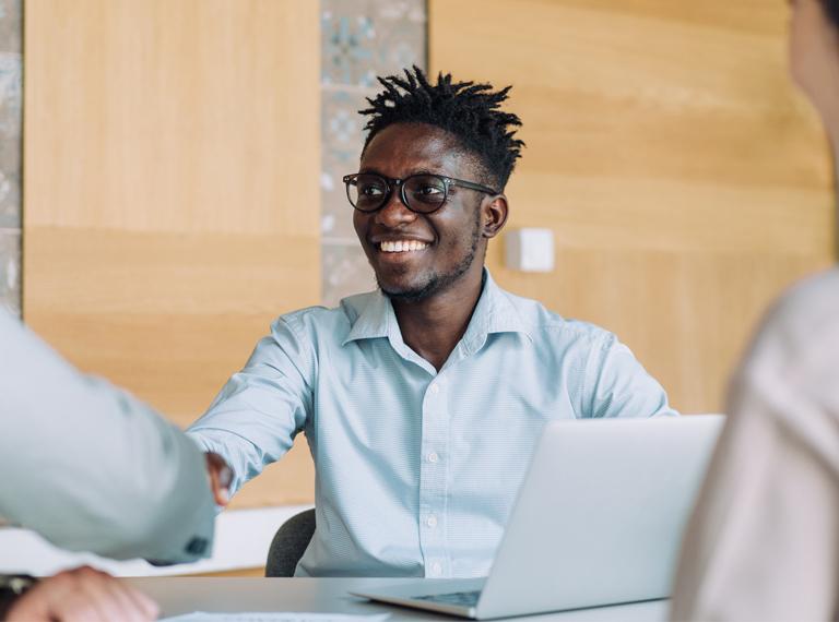 Businesspeople handshaking across the table during a meeting in modern office. Group of business persons in business meeting. Shot of three entrepreneurs on meeting in board room. Creative business team on meeting in the office.