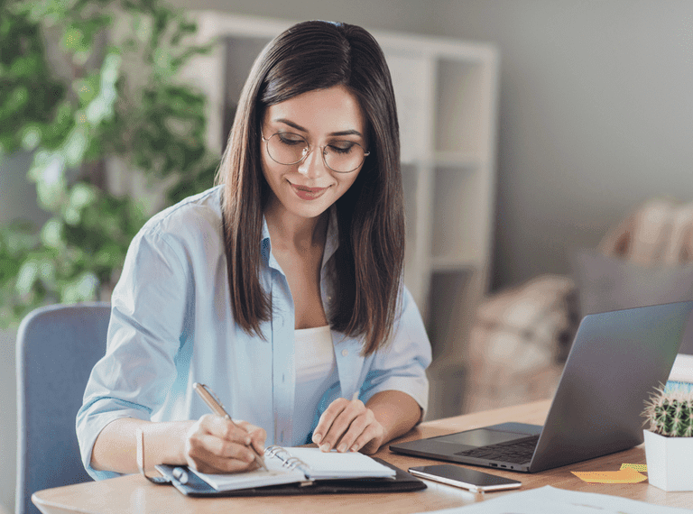 A woman sits at a desk, planning her CV - mobile