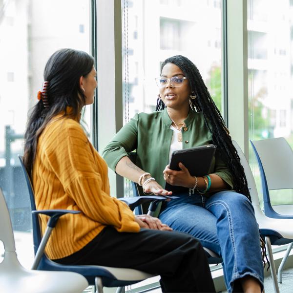 An attentive young woman listens as she receives advice from a caring female counsellor.