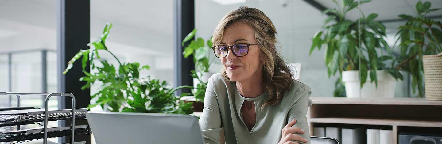 Female office worker sitting at laptop and using AI