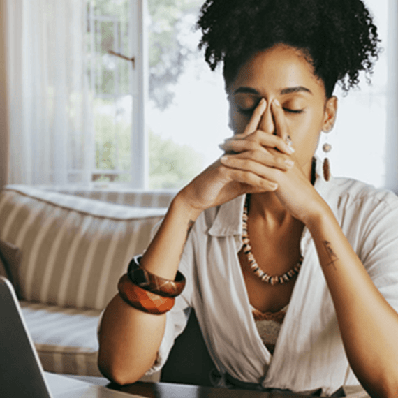 Woman sitting at laptop feeling burnt out at work