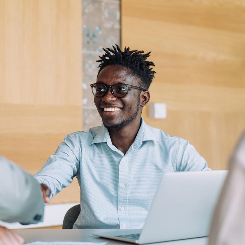 Businesspeople handshaking across the table during a meeting in modern office. Group of business persons in business meeting. Shot of three entrepreneurs on meeting in board room. Creative business team on meeting in the office.