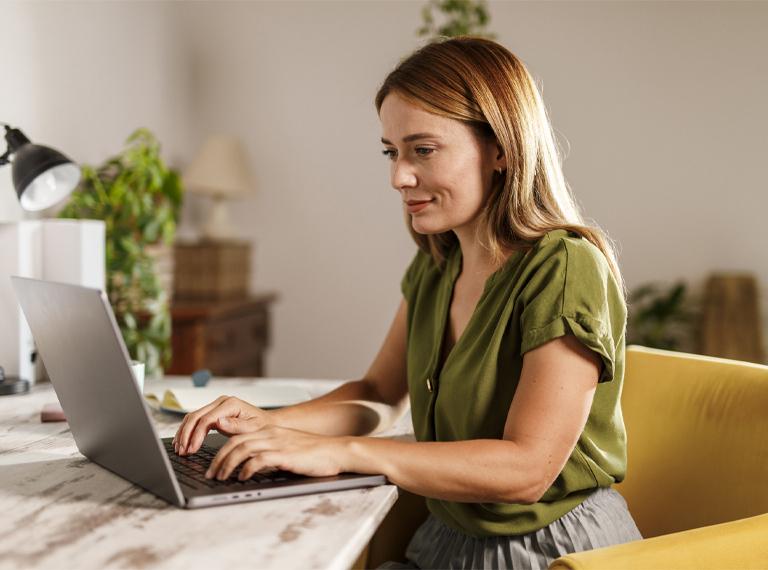 Portrait of diligent mid adult woman using laptop when working on a project, at home office.